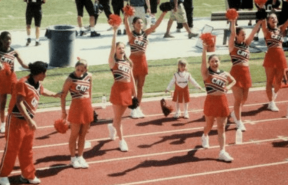 a group of cheerleaders in red and white "" uniforms cheer on a track