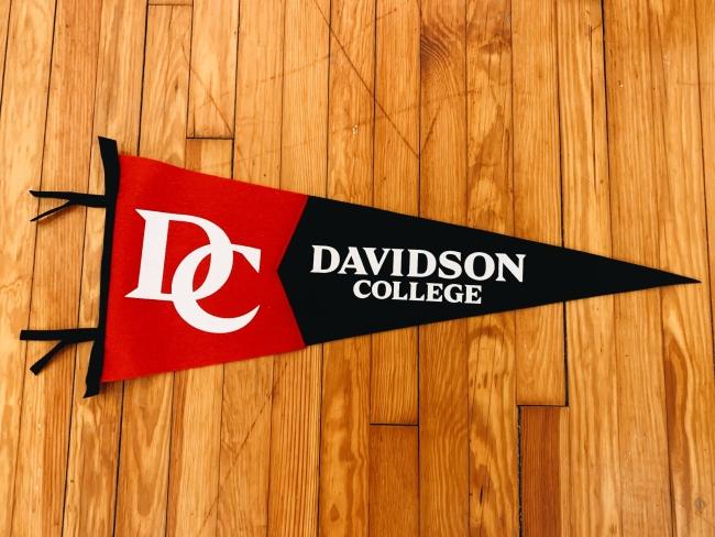 a black and red pennant on a wooden floor that reads " College"