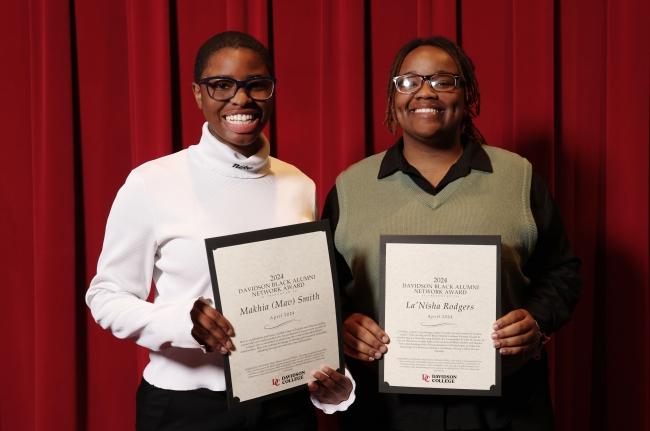 two young Black people holding awards and smiling